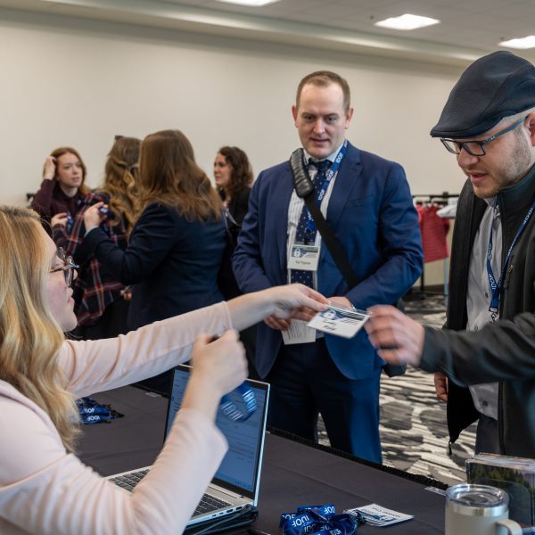 Two conference participants receiving name tags at registration table.