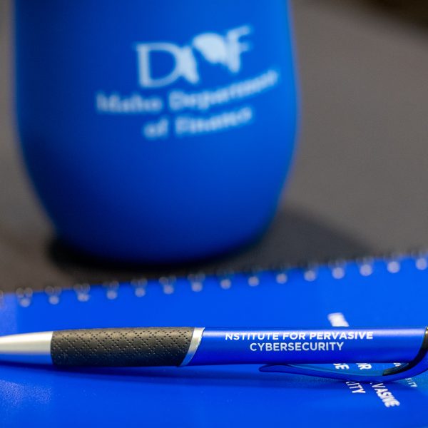 IDOF blue tumbler on table and BSU notebook and pen on table